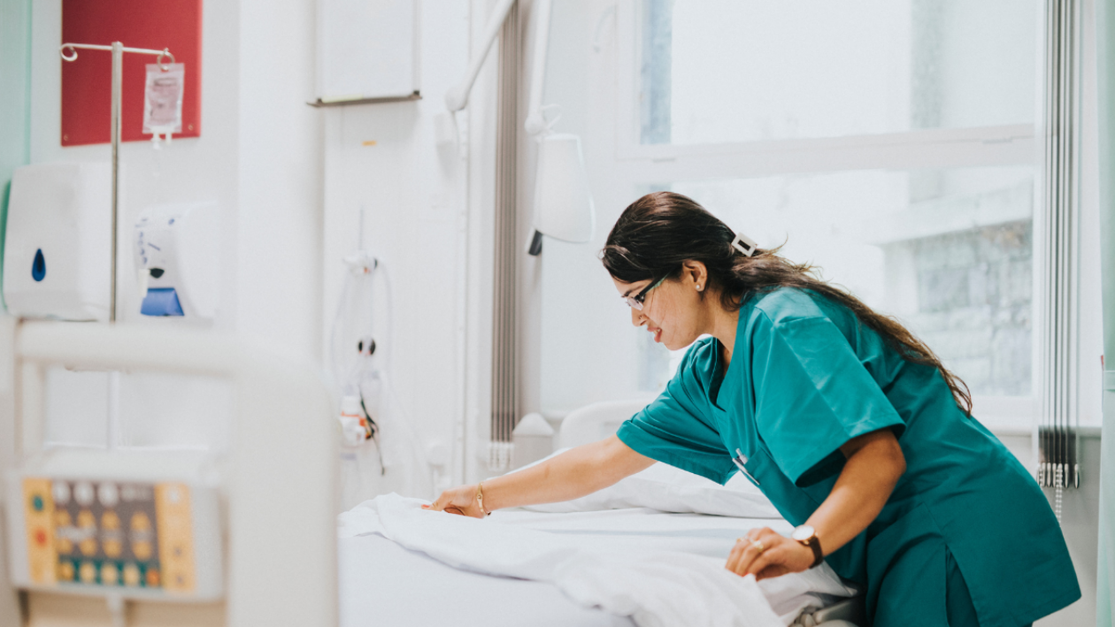 Female nurse making a bed in a hospital room