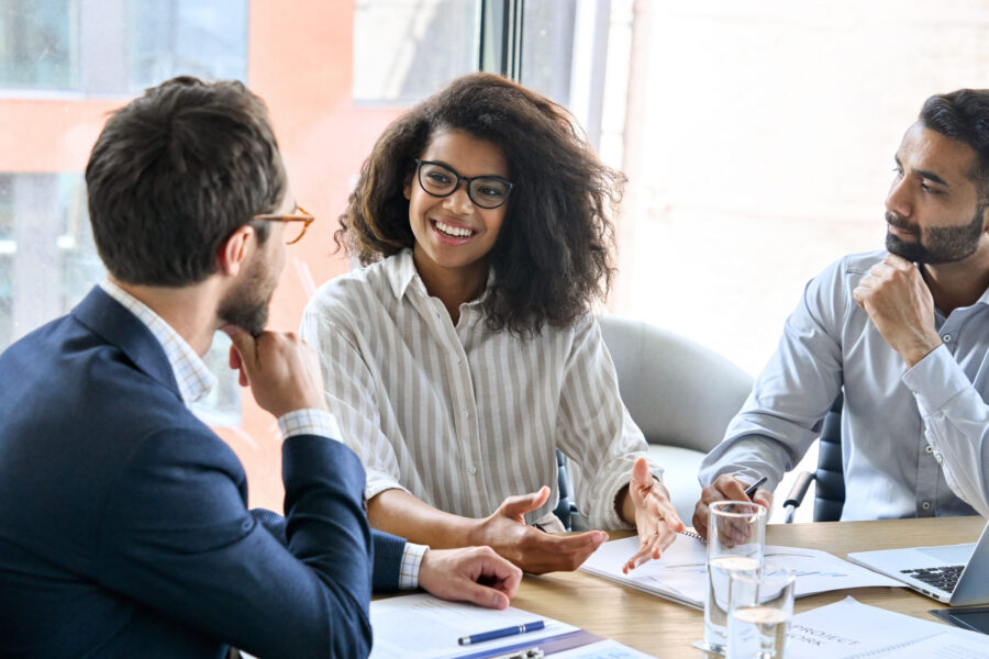 Two businessmen and a business woman sit around a table having a discussion.